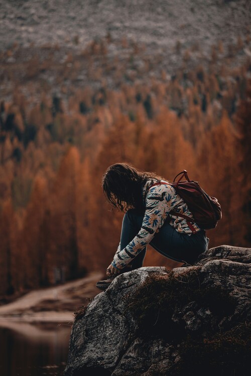 Nachdenkliche Frau sitzt auf einem Stein in der Natur